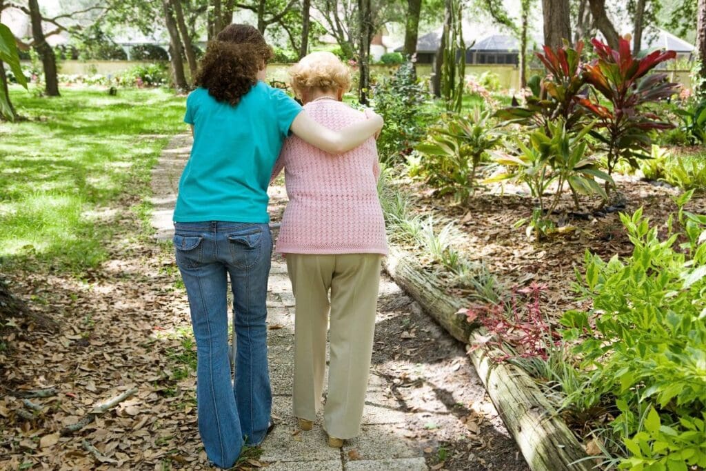 Two women walking arm in arm on a path.