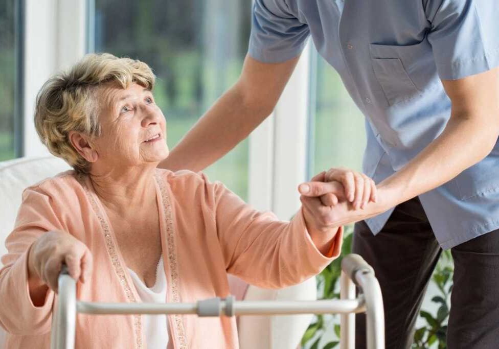 A man helping an older woman in a wheelchair.